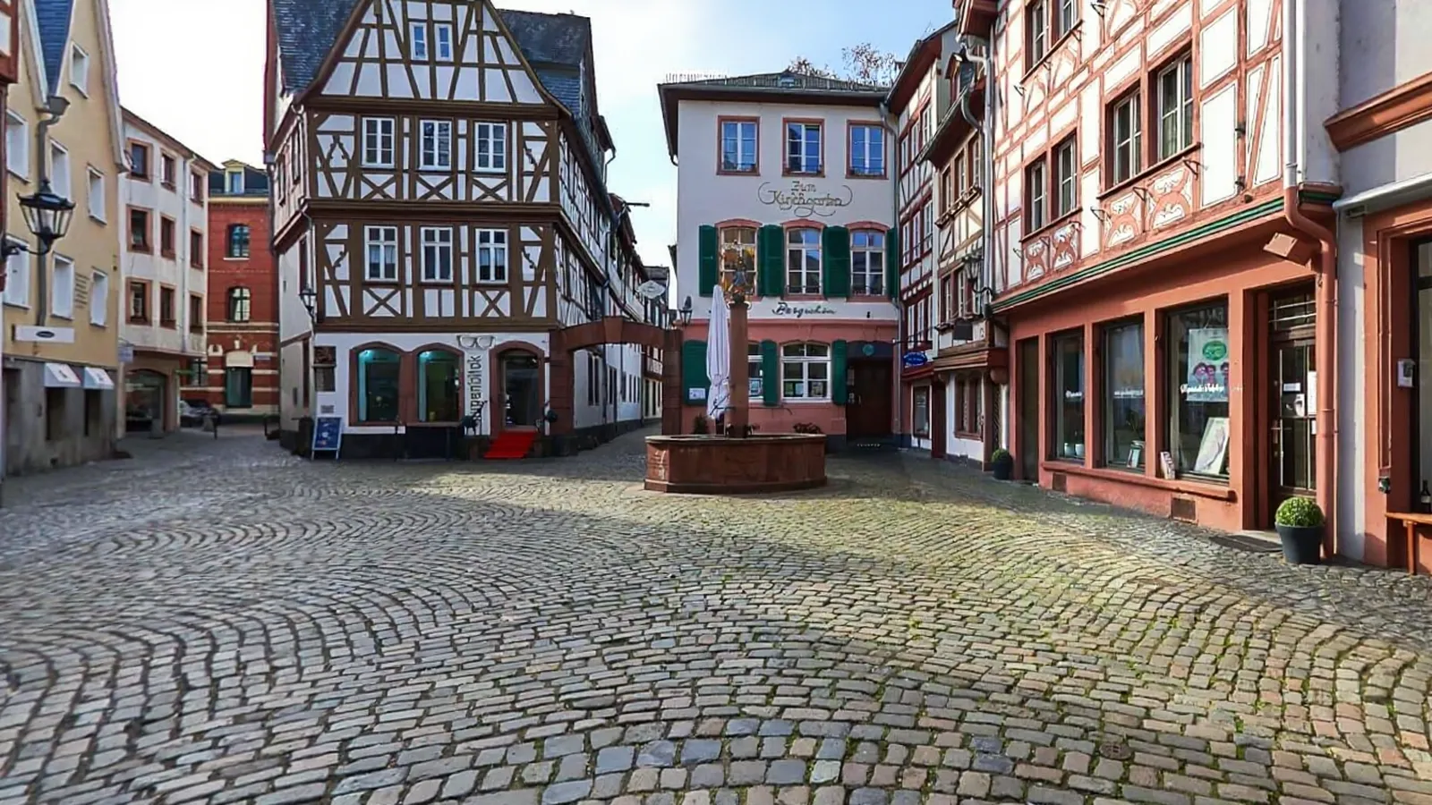 Fachwerkhäuser und Brunnen auf einem Kopfsteinpflasterplatz in der Mainzer Altstadt