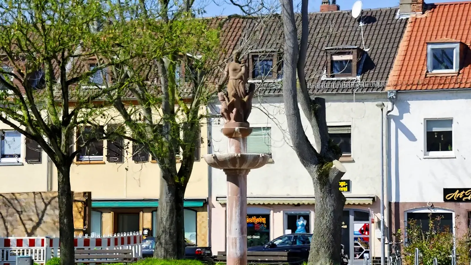 Brunnen mit Figur auf einem Platz vor Wohnhäusern in Mainz-Kostheim