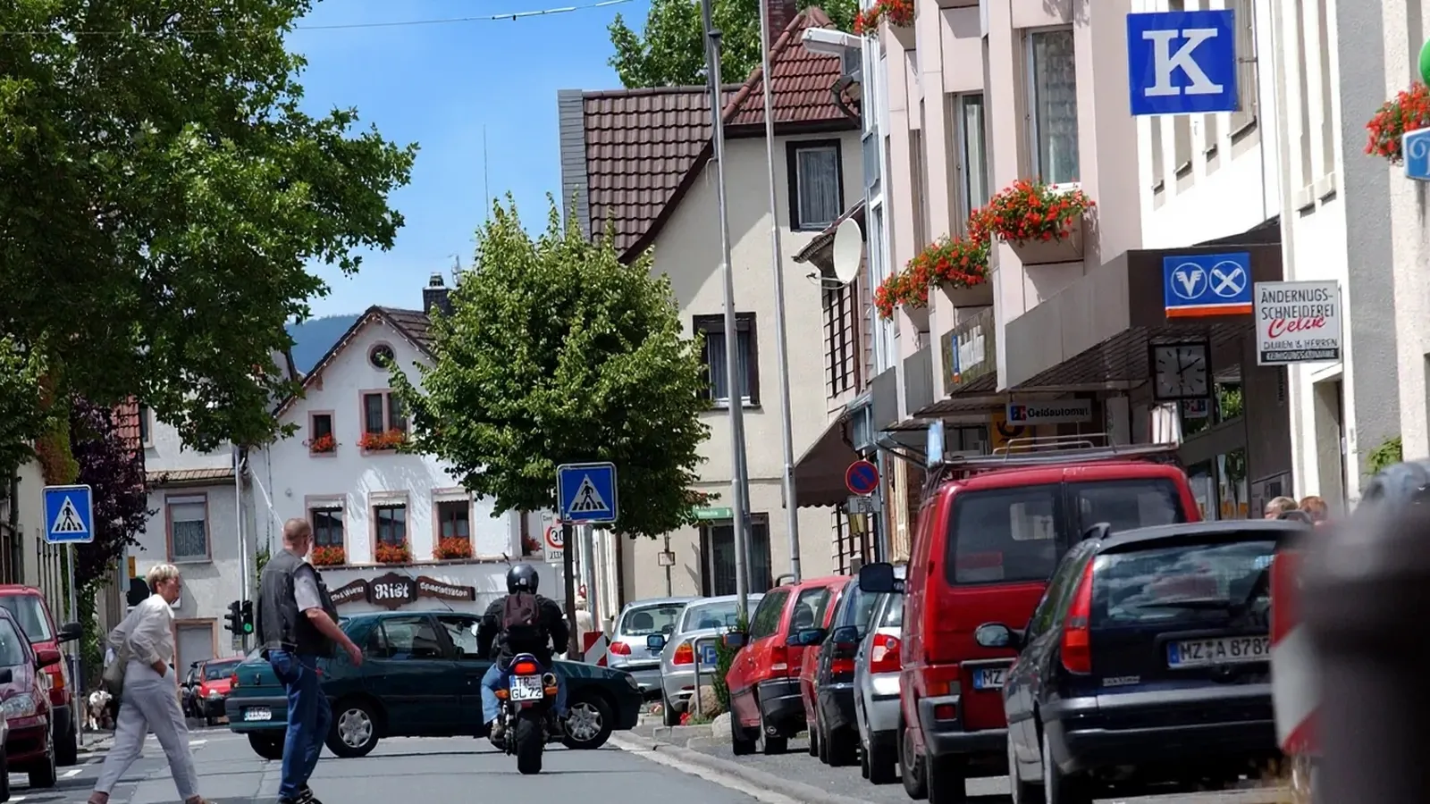 Straße mit Geschäften, Wohnhäusern und Blumenschmuck in Mainz-Mombach