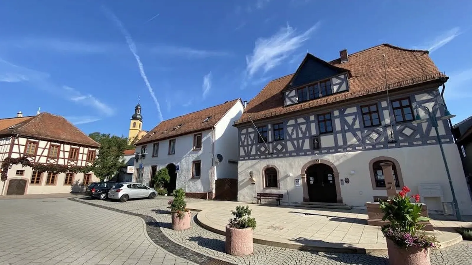 Fachwerkhaus, Kirchturm und Dorfplatz in der Ortsmitte von Nackenheim